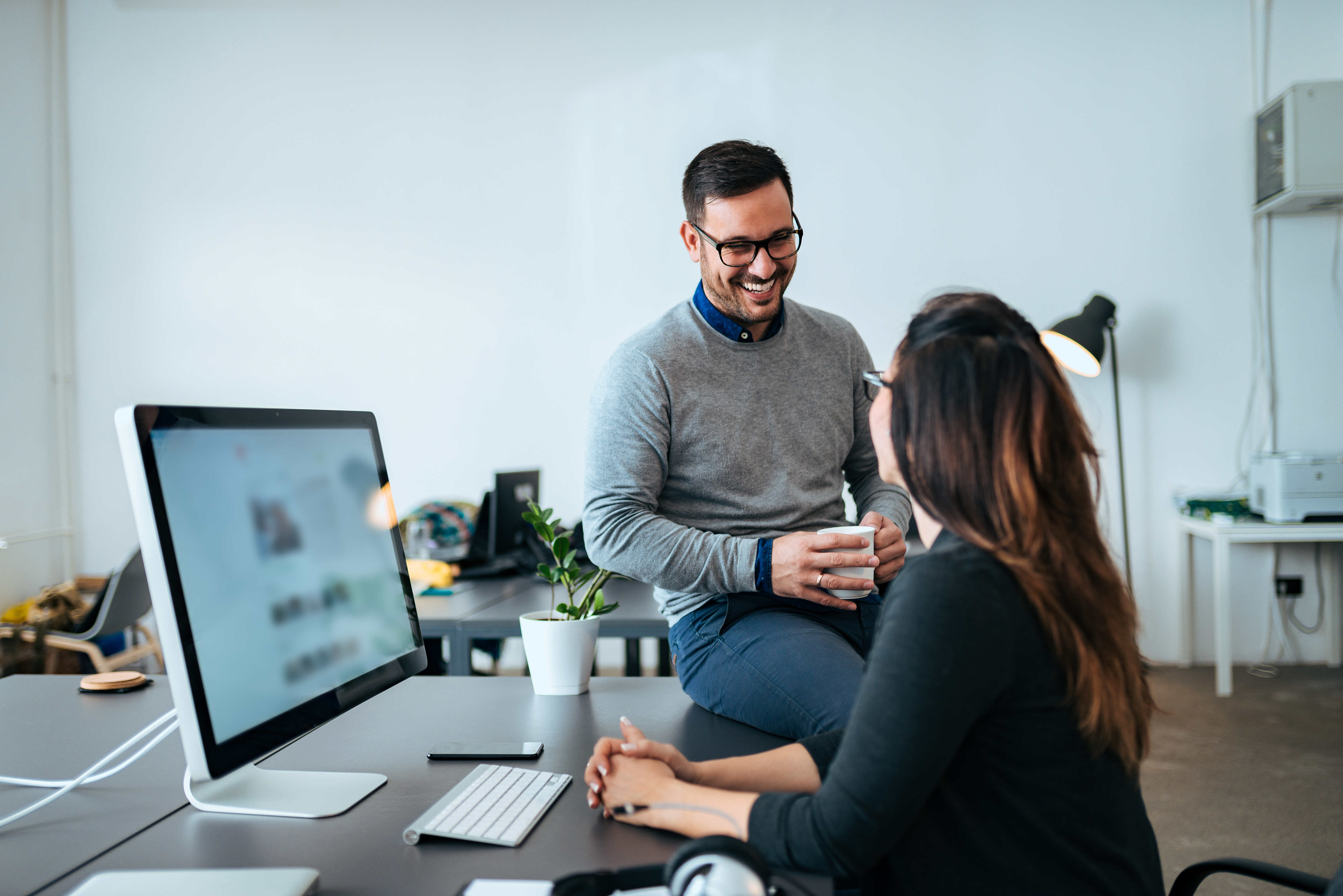 Eine Frau und ein Mann unterhalten sich am Arbeitsplatz in einem Büro