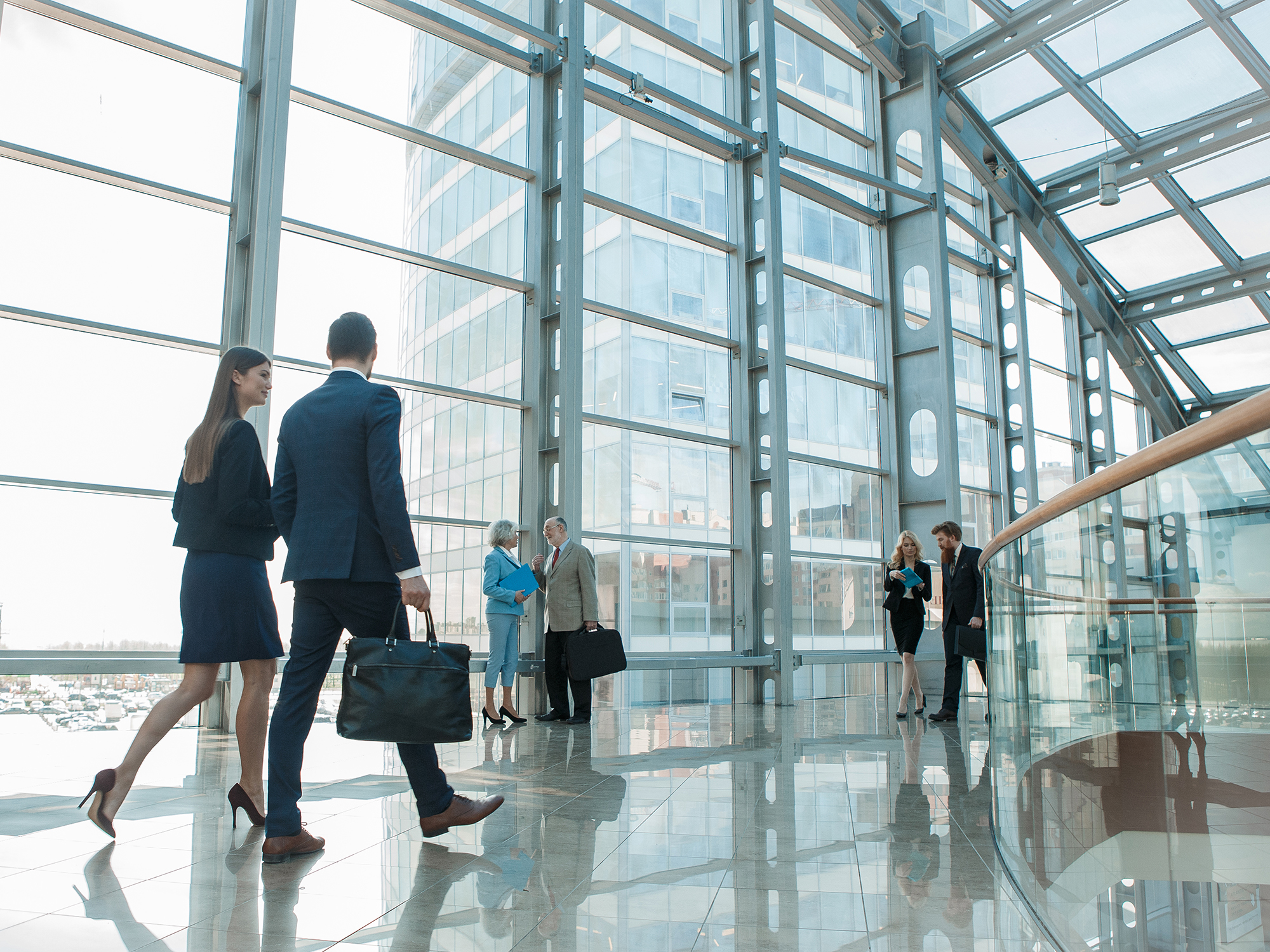 Stor kontorbygning i glas med medarbejdere, der går og står.
