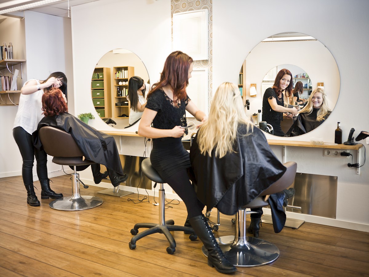 Zwei Friseure schneiden zwei Frauen die Haare beim Friseur
