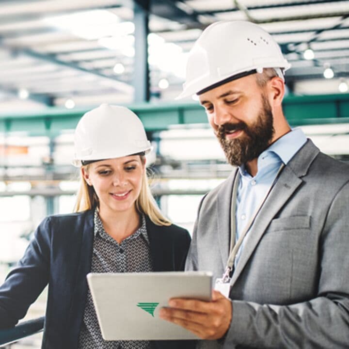 A female and a male engineer reviewing data on a tablet in a production hall.