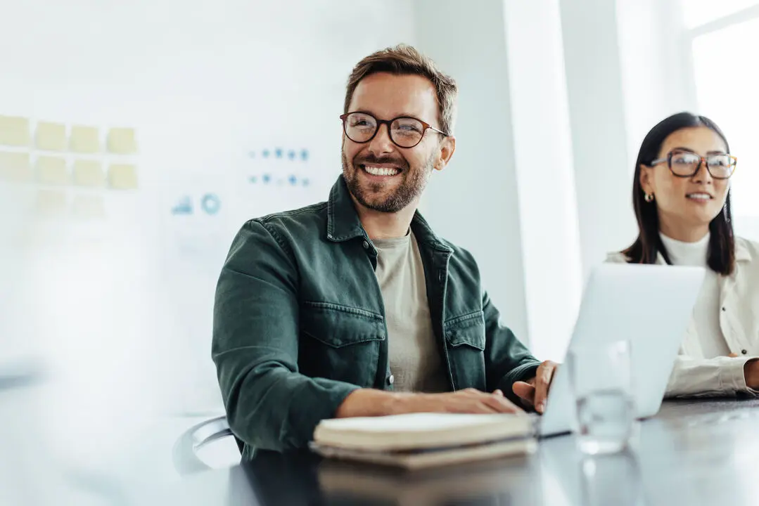 Man sitting in front of a laptop next to a female coworker