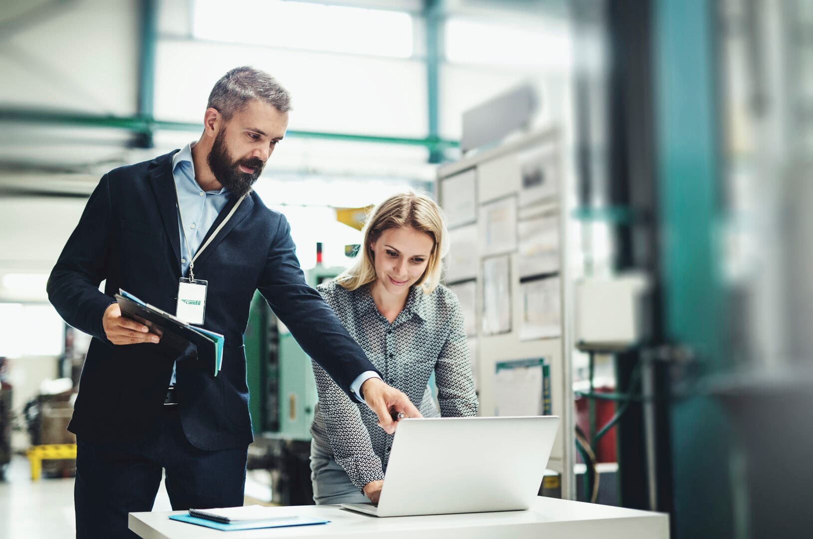 Male and female Camfil employees looking at laptop screen in a factory setting