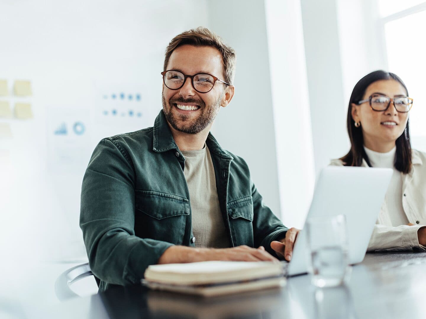 Man and woman with glasses sitting in a meeting smiling