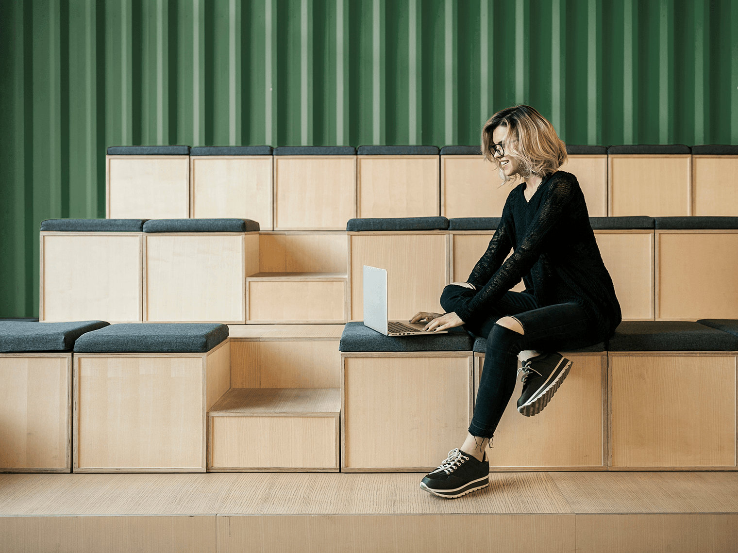 Woman with short hair sitting indoors in front of a laptop