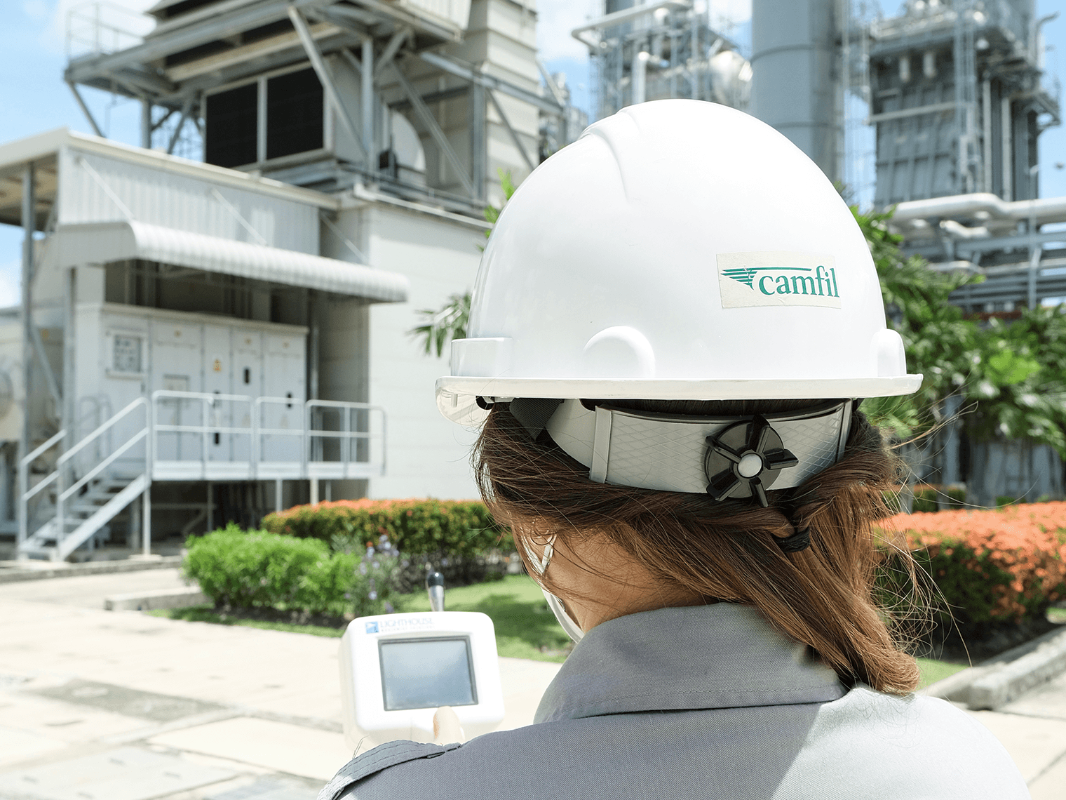 Woman in white hard hat outside a factory