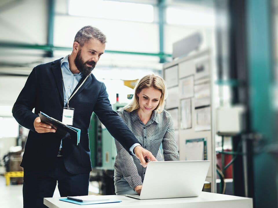 Man and woman in a factory in front of a computer