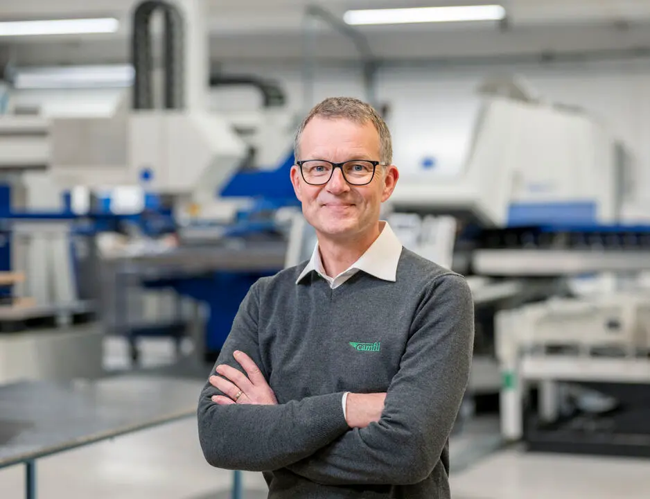 Man standing in factory crossing his arms