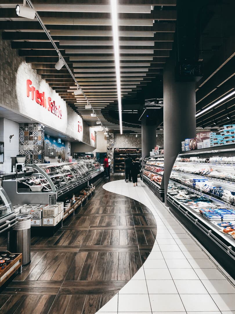 A modern grocery store interior featuring a curved aisle, display cases and bright lightning.