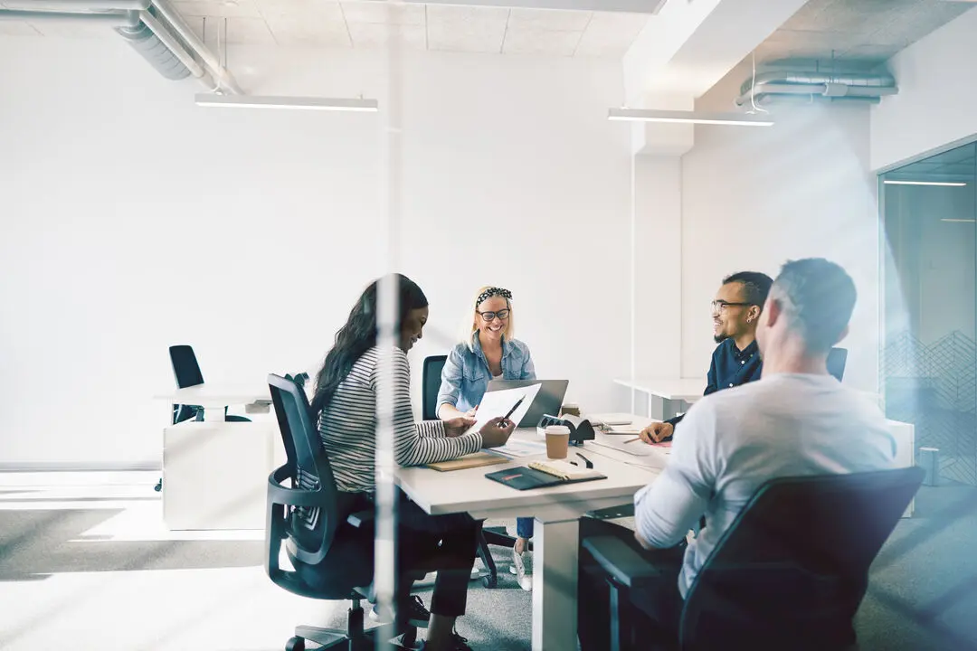 Smiling colleagues meeting together inside of a glass walled off.