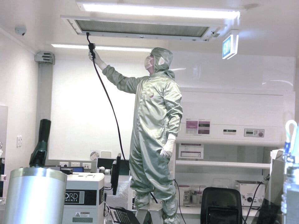 A man in a work suit inspecting a ventilation system.