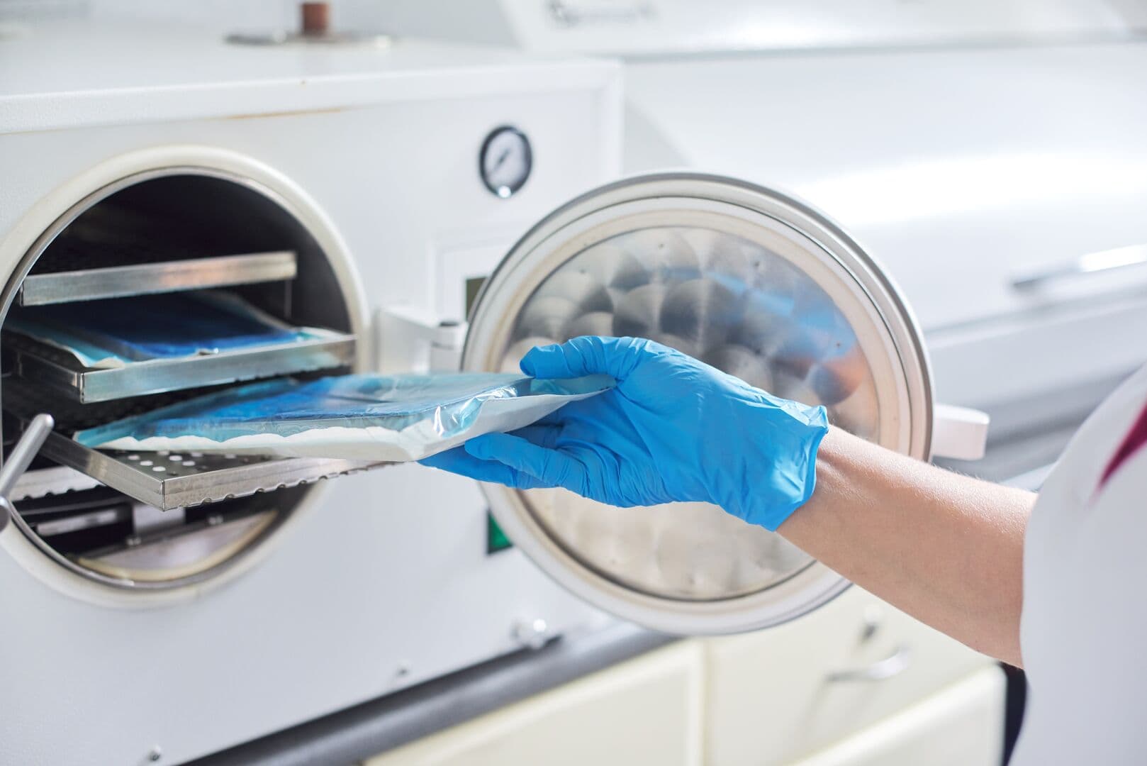 Female nurse doing sterilization of dental medical instruments in autoclave